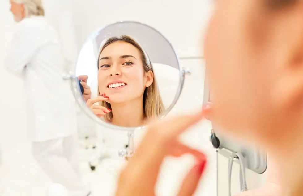 woman looking happily at her face